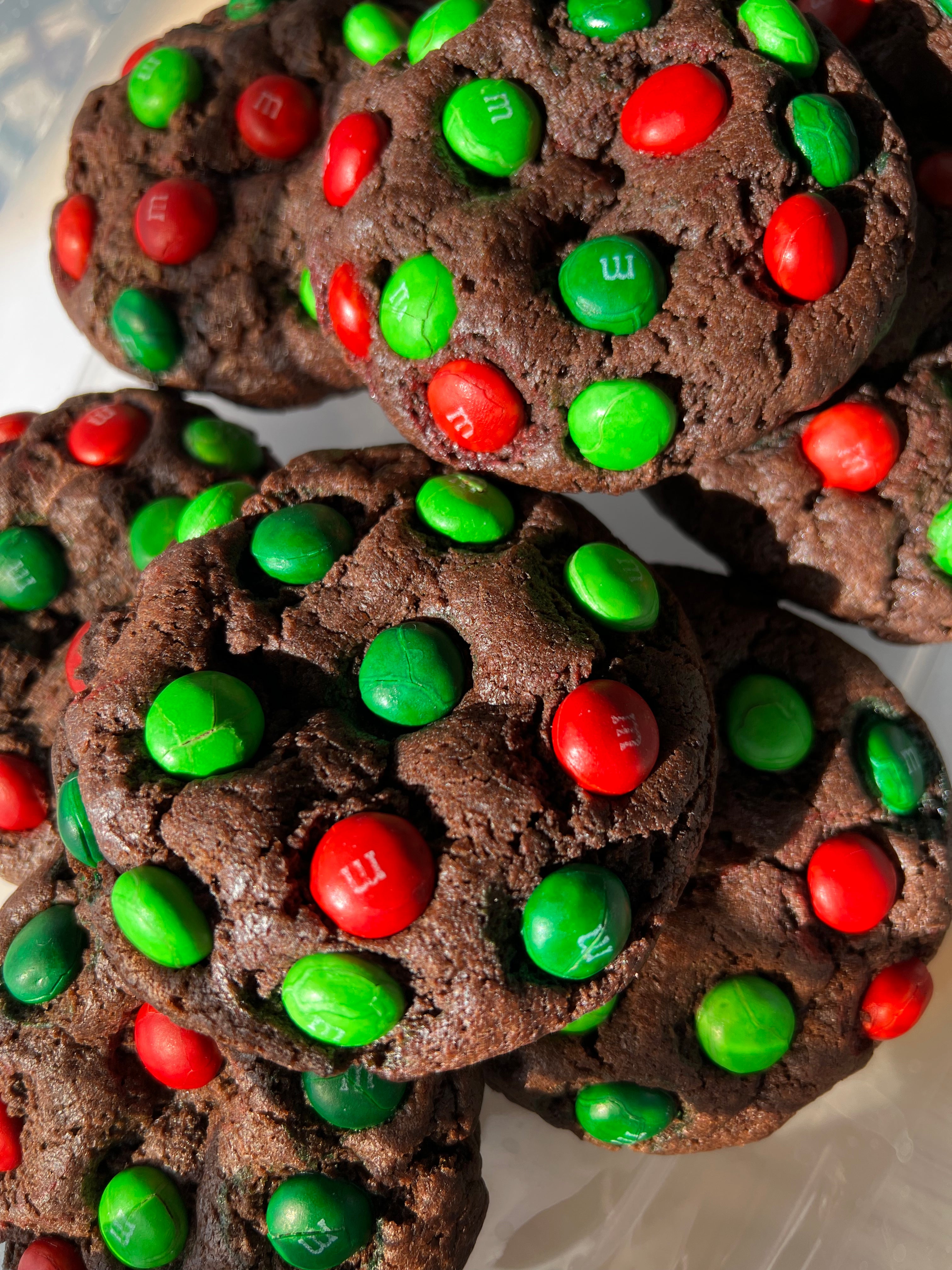 Chocolate cookies with red and green M&M candies on a white plate