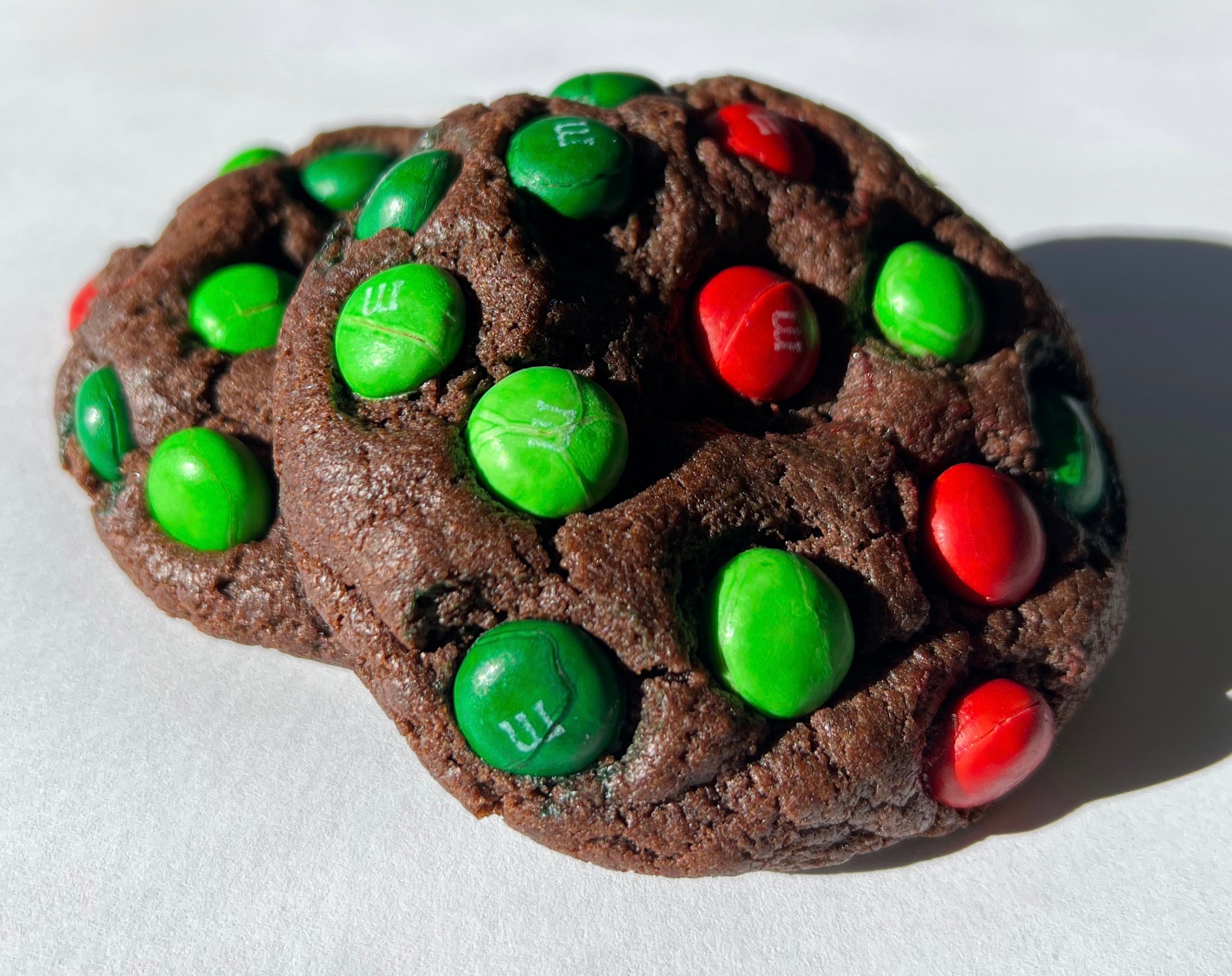 Chocolate cookies with green and red M&M candies on a white background